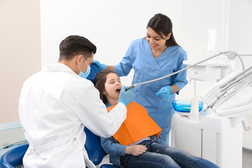 Obraz premium Professional dentist and assistant working with little girl in clinic