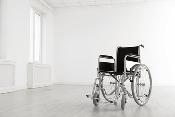 Modern wheelchair in empty room, space for text. Medical equipment
