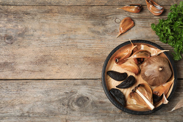 Flat lay composition with black garlic and space for text on wooden table