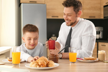 Fototapeta na wymiar Dad and son having breakfast together in kitchen