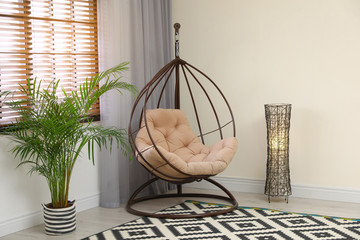 Comfortable swing chair with pillow in room interior