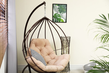 Comfortable swing chair with pillows in room interior