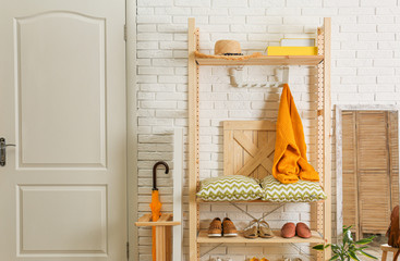 Fototapeta na wymiar Cozy hallway interior with wooden shelving unit. Stylish design idea