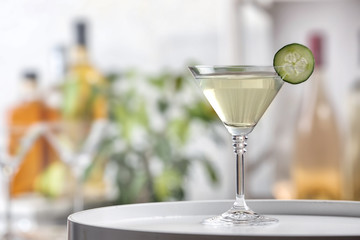 Glass of tasty cucumber martini on table indoors, space for text