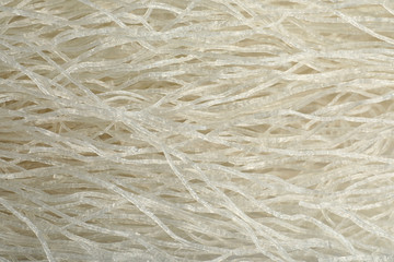 Tasty uncooked rice noodles as background, top view