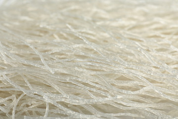 Tasty uncooked rice noodles as background, closeup