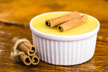 Typical Brazilian dessert, sweet of mingua, called in Brazil of curau. Typical sweet of June party. Brazilian sweet corn, corn mousse on a wooden background with copy space.
