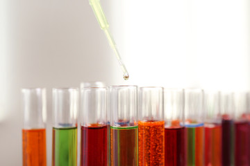 Dripping color liquid into test tube, closeup. Solution chemistry