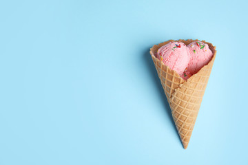 Delicious ice cream in wafer cone on blue background, top view. Space for text