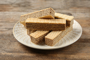 Plate of delicious wafers on brown wooden background