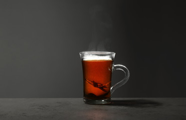 Glass cup of hot leaf tea on stone table against grey background, space for text