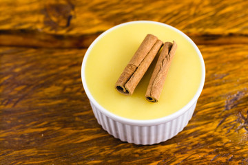 Typical Brazilian dessert, sweet of mingua, called in Brazil of curau. Typical sweet of June party. Brazilian sweet corn, corn mousse on a wooden background with copy space.