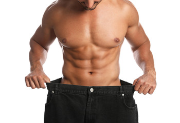 Young man with slim body in old big size jeans on white background, closeup view