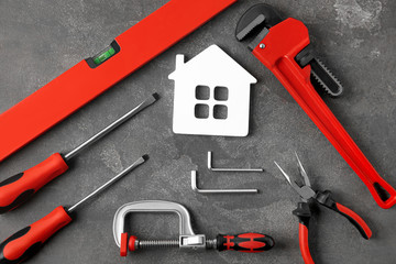 Set of repair tools and house figure on grey stone background, flat lay