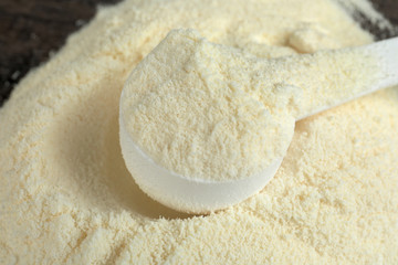 Pile of protein powder and scoop on table, closeup