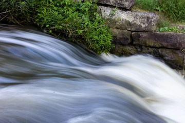 Long exposure photo of flowing water in the river. Close up photo with moody soft light.