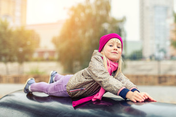 Portrait of cute caucasian blond little girl having fun playing at modern outdoor playground at city park in autumn. Adorable young happy child enjoying and smiling during leisure activities