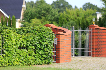 Ogrodzenie, metalowa brama i mur z cegły czerwonej. - obrazy, fototapety, plakaty