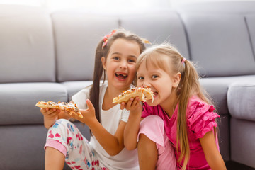 Portrait of cute little girl sitting and eating pizza
