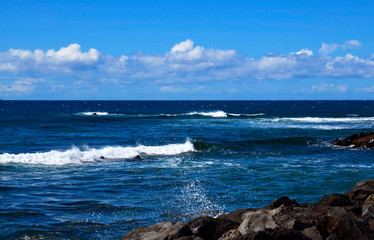 Atlantic Ocean seascape.Waves splashing on rocky coast and blue sky with clouds.Tenerife,Canary Islands,Spain. Travel concept.