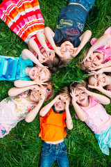 A group of children lying on the green grass in the Park. The interaction of the children.