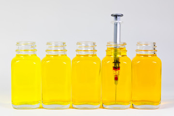Bottles with yellow serum in different shades and a injection needle, syringe