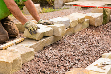 Man landscaping with natural stones -  Building of a dry stone wall