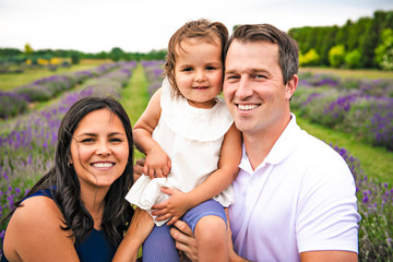 Fototapeta premium Happy family mother, father and daughter having fun in lavender field