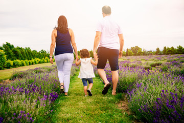 Happy family mother, father and daughter having fun in lavender field