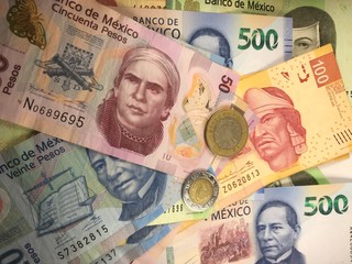 Fototapeta na wymiar Mexican peso bills spread randomly over a flat surface