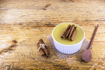 Dessert of curau. Brazilian sweet corn, corn mousse with cinnamon on a wooden background. Typical Brazilian dessert, sweet of June party. Dessert, canjica or Jimbelê.