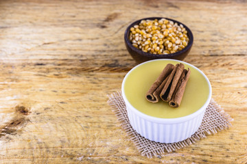 Dessert of curau. Brazilian sweet corn, corn mousse with cinnamon on a wooden background. Typical Brazilian dessert, sweet of June party. Dessert, canjica or Jimbelê.