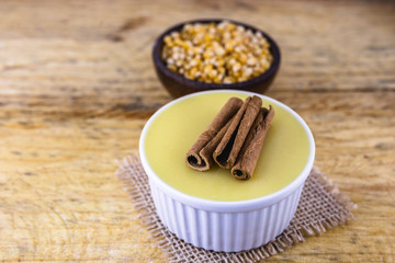 Dessert of curau. Brazilian sweet corn, corn mousse with cinnamon on a wooden background. Typical Brazilian dessert, sweet of June party. Dessert, canjica or Jimbelê.