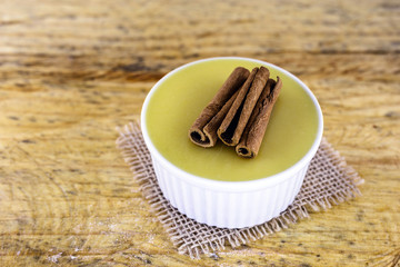 Dessert of curau. Brazilian sweet corn, corn mousse with cinnamon on a wooden background. Typical Brazilian dessert, sweet of June party. Dessert, canjica or Jimbelê.