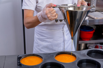 Pastry chef in the kitchen makes passion fruit confit. Cook pours passion fruit confit into the big molds. Master class in the kitchen. The process of cooking. Step by step. Tutorial. Close-up