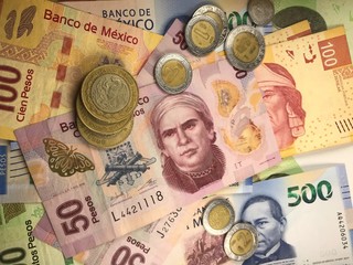 Mexican peso bills spread randomly over a flat surface