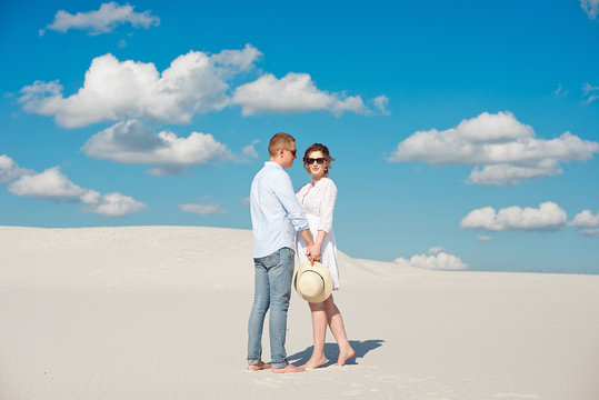 Young couple enjoying the sunset in the dunes. Romantic traveler walks in the desert. Adventure travel lifestyle concept.