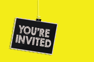 Writing note showing You re are Invited. Business photo showcasing Please join us in our celebration Welcome Be a guest Hanging blackboard message communication sign yellow background