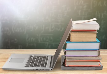 Stack of books with laptop on table