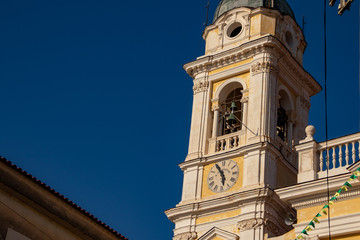 Fototapeta na wymiar The bell tower of the main church of the town, with the clock in the foreground.