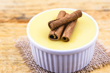 Dessert of curau. Brazilian sweet corn, corn mousse with cinnamon on a wooden background. Typical Brazilian dessert, sweet of June party. Dessert, canjica or Jimbelê.