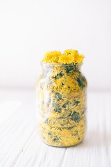 Dandelions in a glass jar on a white background