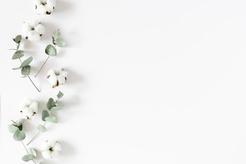 Flowers creative composition. Cotton flowers, eucalyptus branches and leaves on white background. Flat lay, top view, copy space - obrazy, fototapety, plakaty