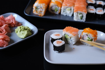 Sushi roll with seafood and soy sauce, wasabi and ginger. Sushi roll with salmon on a black table