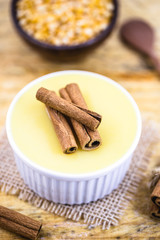 Dessert of curau. Brazilian sweet corn, corn mousse with cinnamon on a wooden background. Typical Brazilian dessert, sweet of June party. Dessert, canjica or Jimbelê.