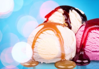 Scoops of ice cream with syrup on blue background