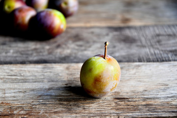 Plums in the garden in the morning, on old boards.