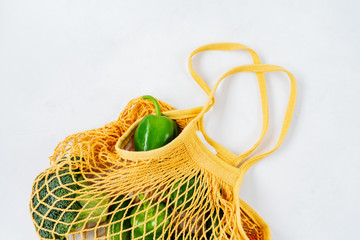 Products and Fresh vegetables in string mesh bag on a white background..Zero waste shopping concept. Recycling. Awareness consumption. Sustainable lifestyle.