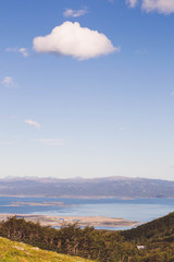 Landscape of a lake with mountains, clear sky with a few clouds 