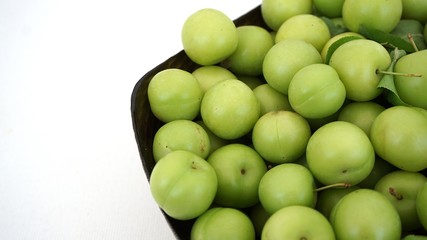 green plums, fresh plums, sour plums in a container, green and sour plums close-up,